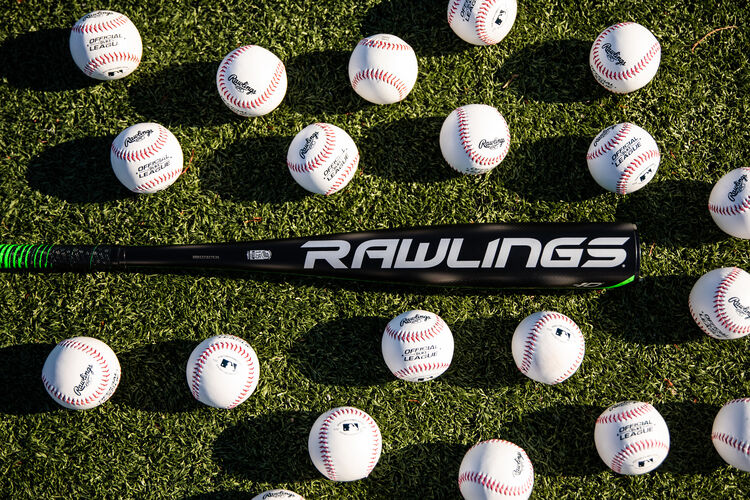 A Rawlings 2021 USSSA 5150 bat laying on a field with baseballs around it - SKU: UT1510