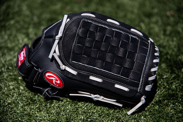 A black RSB Basket web glove lying in the grass on a field - SKU: RSB140GB