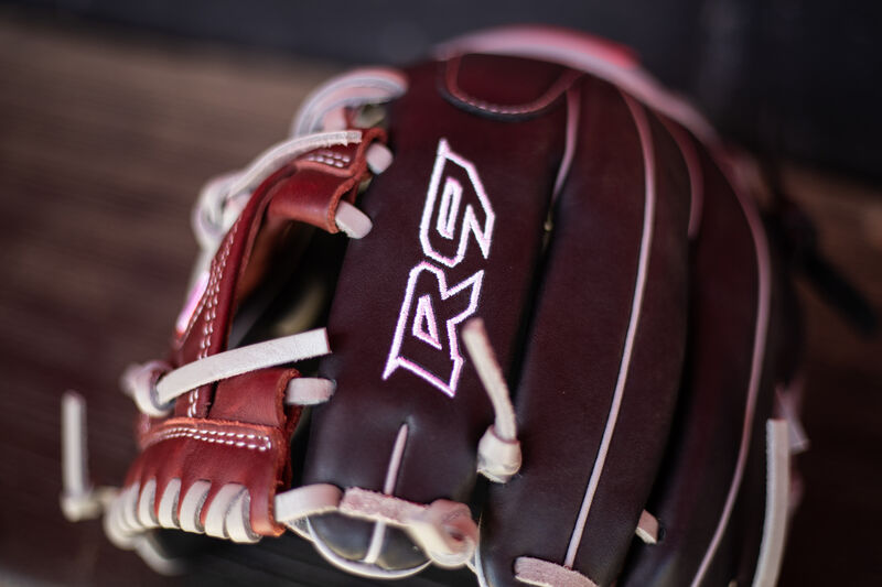 R9 Logo on the index finger of a R9 Series infield glove sitting on the bench in a dugout - SKU: R9204-2BSG