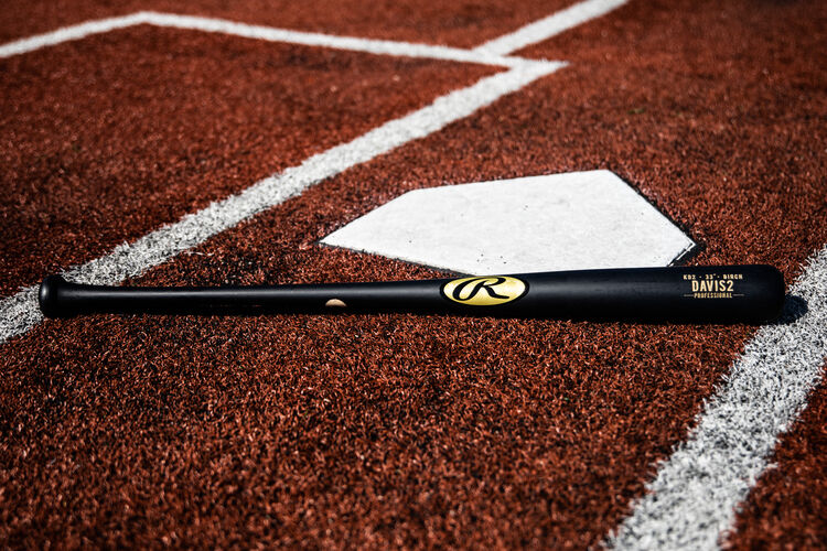 A black Khris Davis Pro Label bat lying next to home plate - SKU: KD2PL