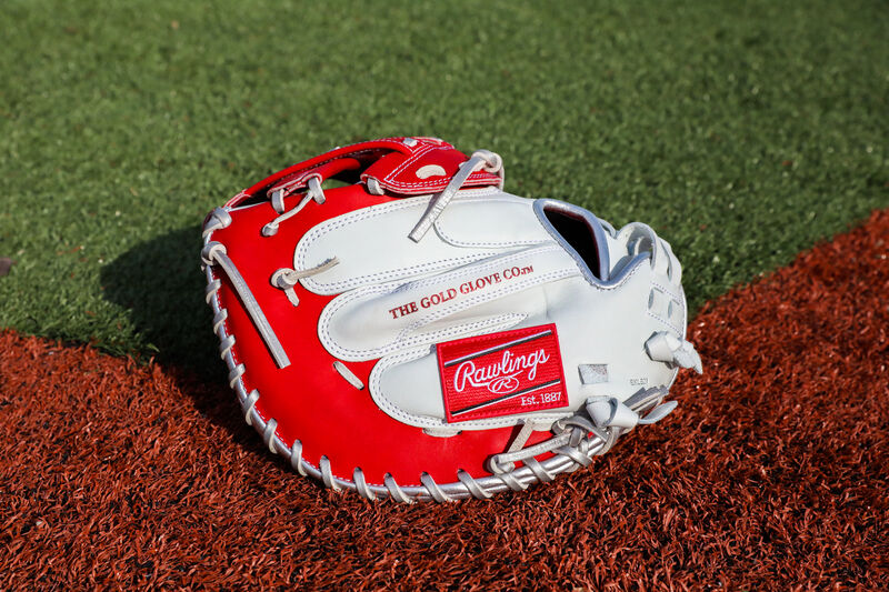 A white/scarlet Liberty Advanced Color Series catcher's mitt with a red Rawlings patch on a field - SKU: RLACM34FPWSP loading=