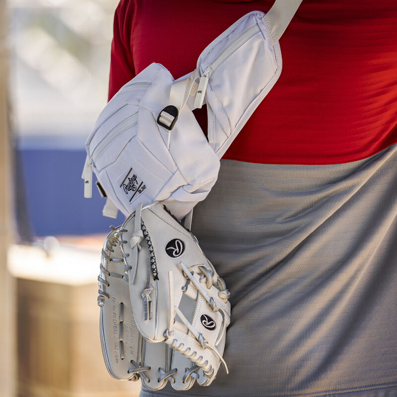 A glove clipped to a white Rawlings sling bag on a players back - SKU: RSLINGBG