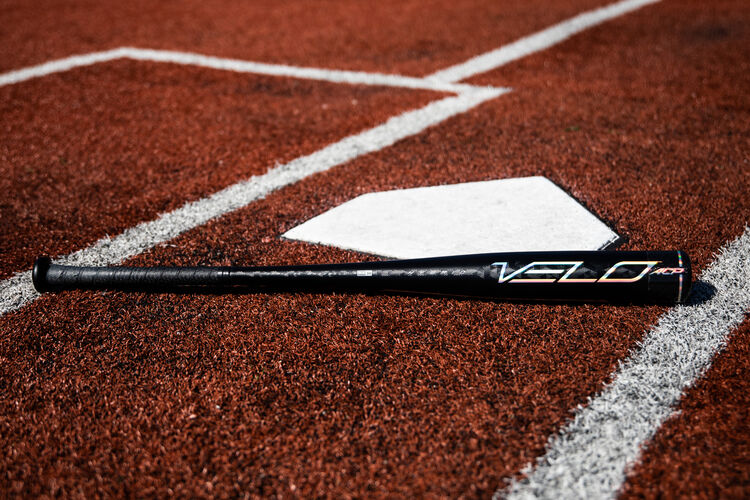 A black/silver Rawlings Velo ACP BBCOR bat on a field next to home plate - SKU: BBZV3