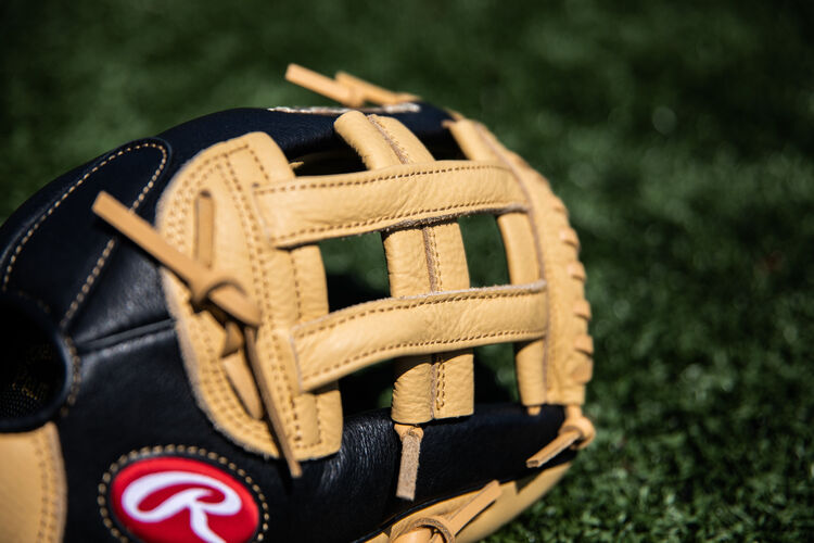 A camel H-web on a Prodigy outfield glove lying on a field - SKU: P120CBH