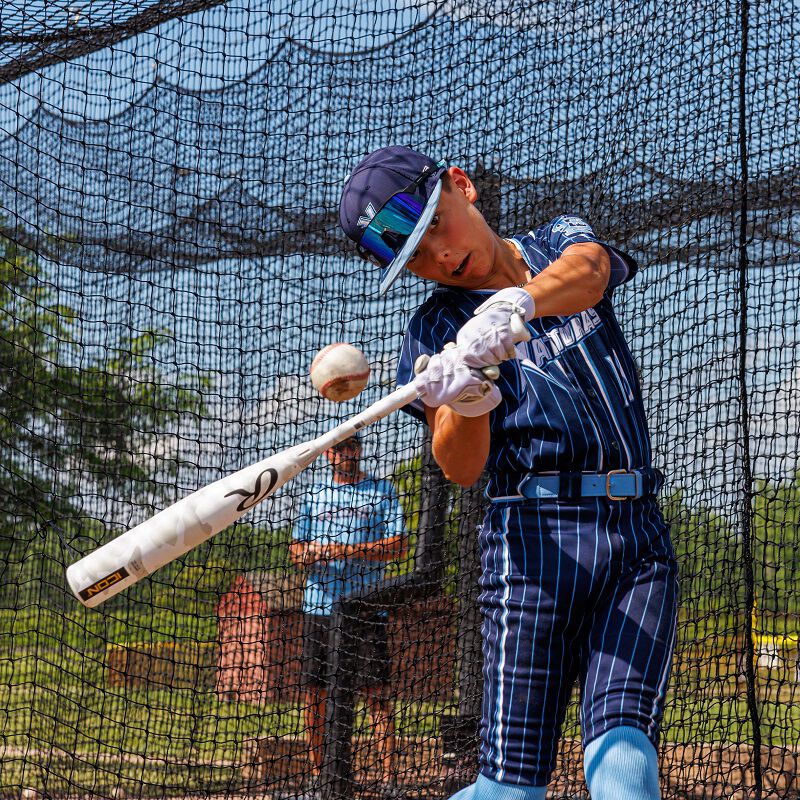 Picture of a player hitting a ball in a batting cage with a 2025 Icon USSSA bat