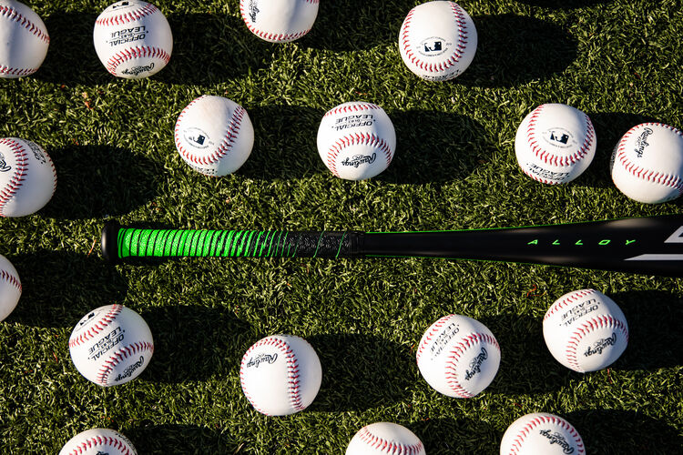 Handle of a 2021 Rawlings 5150 bat laying on a field surrounded by baseballs - SKU: UT1510