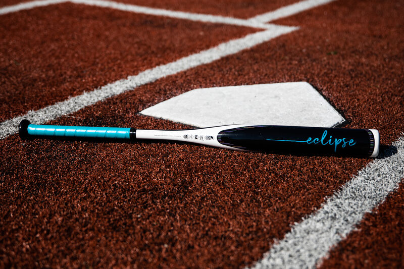 A Rawlings Eclipse fastpitch bat lying on a field next to home plate - SKU: FPZE12