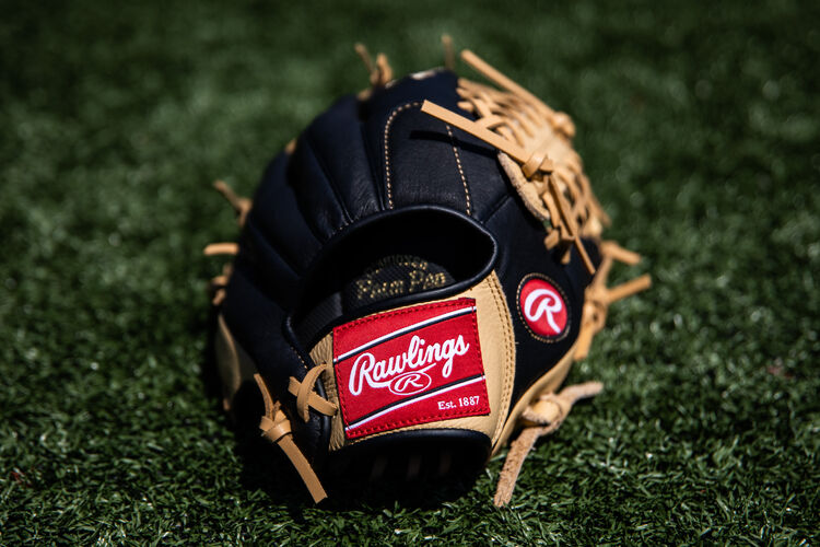 Rawlings patch on a Rawlings youth Prodigy glove lying on a field - SKU: P115CBMT