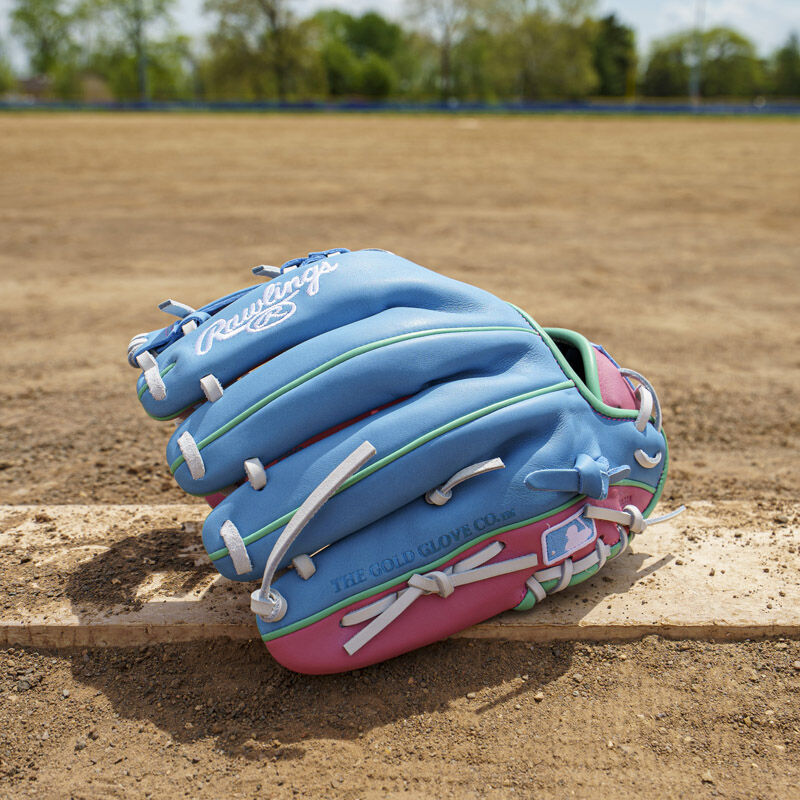 Picture of the back of a columbia blue/pink Exclusive Rawlings NXT Series 11.5" Infield Glove on a pitching rubber