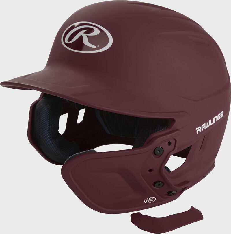 A maroon MEXTR attached to a Mach batting helmet with the removable TPU piece off to show the hardware