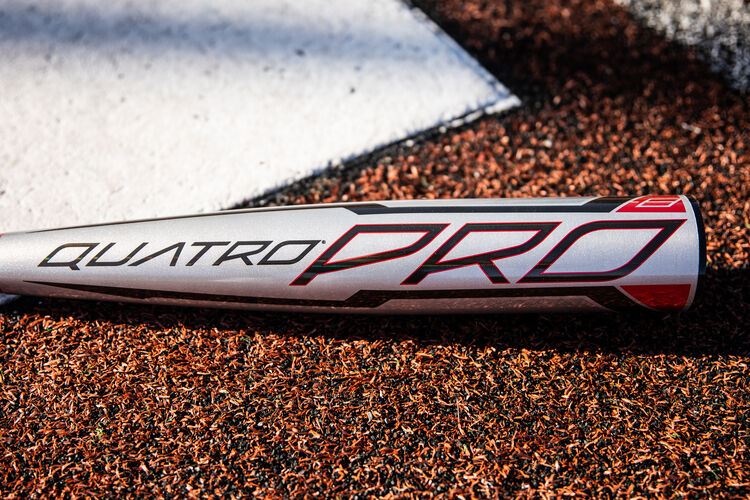 A black Quatro Pro logo on the gray barrel of a USA Quatro Pro bat next to home plate - SKU: US1Q8