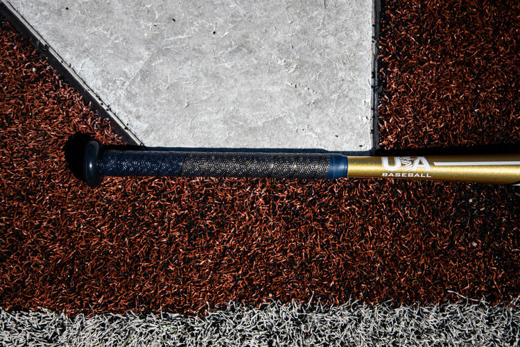 Navy batting grip of a Threat USA bat lying next to home plate - SKU: USZT12