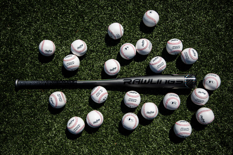 A Rawlings USA Velo ACP bat lying on a field surrounded by baseballs - SKU: USZV10