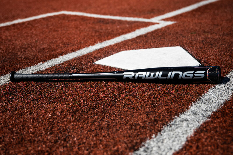 A Rawlings Velo ACP bat lying next to home plate on a field - SKU: BBZV3