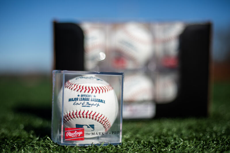 An MLB ball in a display cube sitting in front of a box of a dozen balls on a field - SKU: ROMLB-R image number null