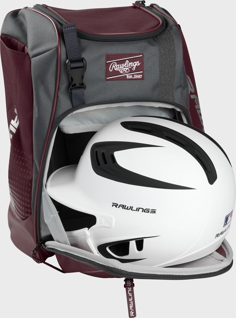 A white/black helmet in the main compartment of a maroon Rawlings Franchise backpack - SKU: FRANBP-MA