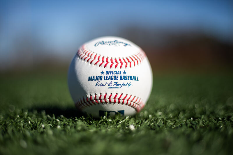 A Rawlings MLB baseball lying in the grass on a field - SKU: ROMLB