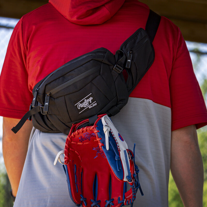 A glove clipped to a black Rawlings sling bag on a players back - SKU: RSLINGBG