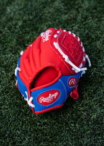 Red Rawlings logo on a red/blue Players Series youth glove lying on a field - SKU: PL91SR