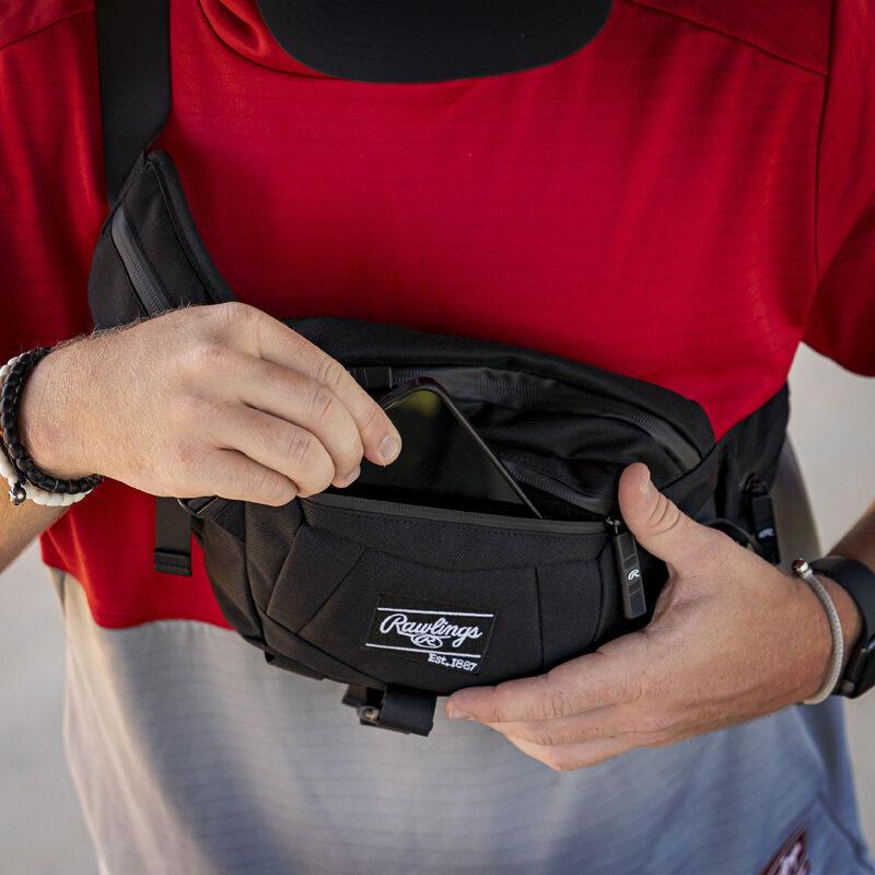 A player pulling his phone out of the front pocket of a black Players sling bag - SKU: RSLINGBG