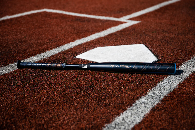 A Rawlings Quatro Pro End Load fastpitch bat lying next to home plate on a field - SKU: FPPE10
