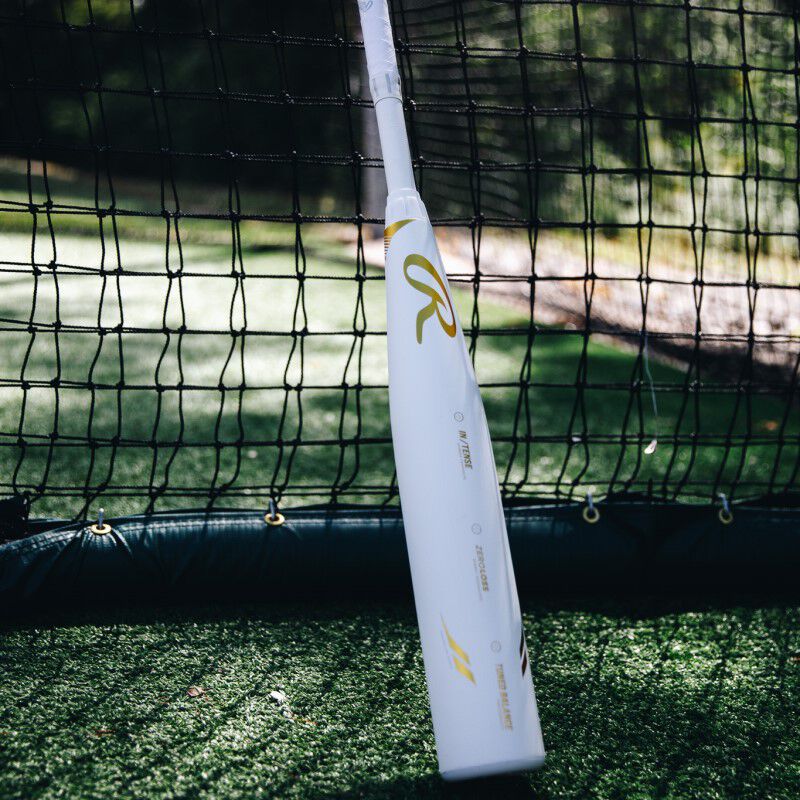 A white Rawlings Icon USSSA bat leaning against a batting cage - SKU: RUT4I