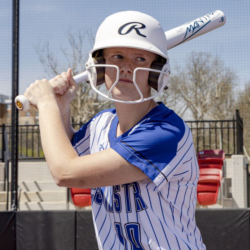 A softball player in her batting stance wearing a white Rawlings Mach Hi-Viz helmet - SKU: MCHVIZ