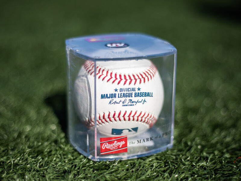 An Official MLB baseball in a display cube sitting in grass on a field - SKU: ROMLB-R