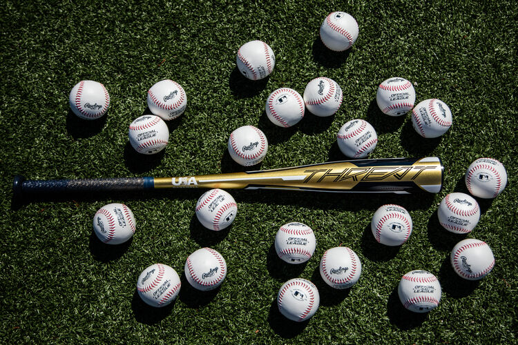 A Rawlings Threat USA bat lying on a field surrounded by baseballs - SKU: USZT12