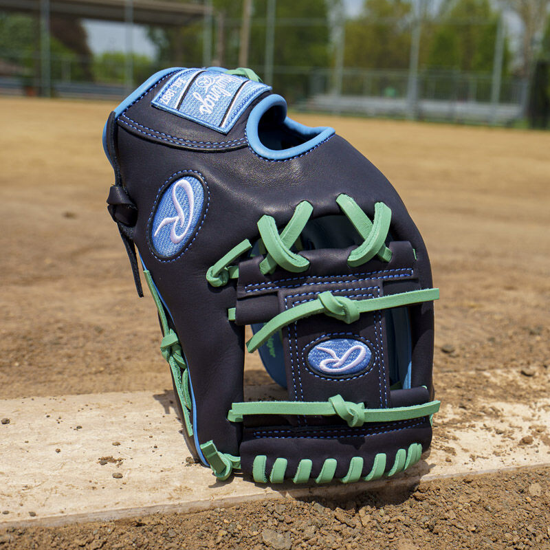 Picture of a navy exclusive Rawlings NXT Series 11.5" infield glove standing on its fingertips on a pitching rubber