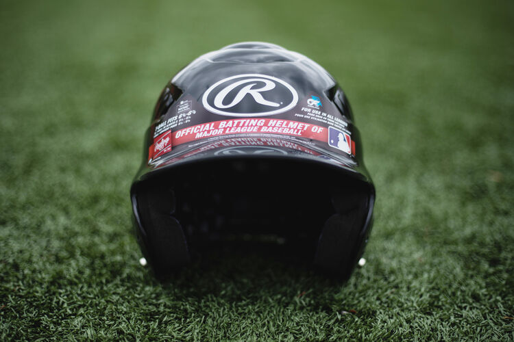 Front of a black Rawlings Coolflo helmet with an Oval-R logo sitting on a field - SKU: RCFH