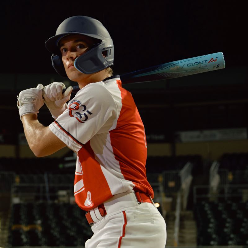 A player standing up to bat with a blue Clout AI BBCOR bat