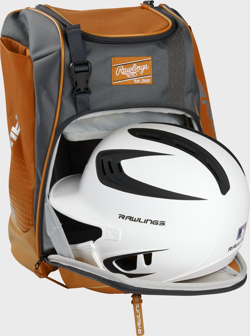 A white/black helmet in the main compartment of an orange Rawlings Franchise backpack - SKU: FRANBP-O