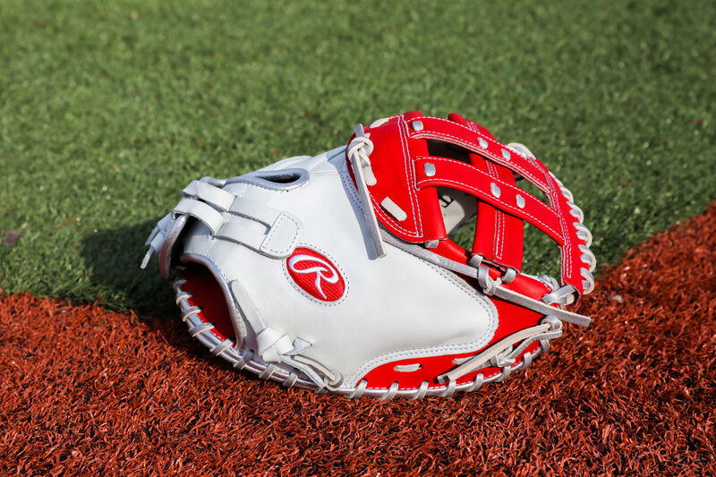 A white/scarlet Liberty Advanced Color Series 34-Inch catcher's mitt with on a field - SKU: RLACM34FPWSP loading=