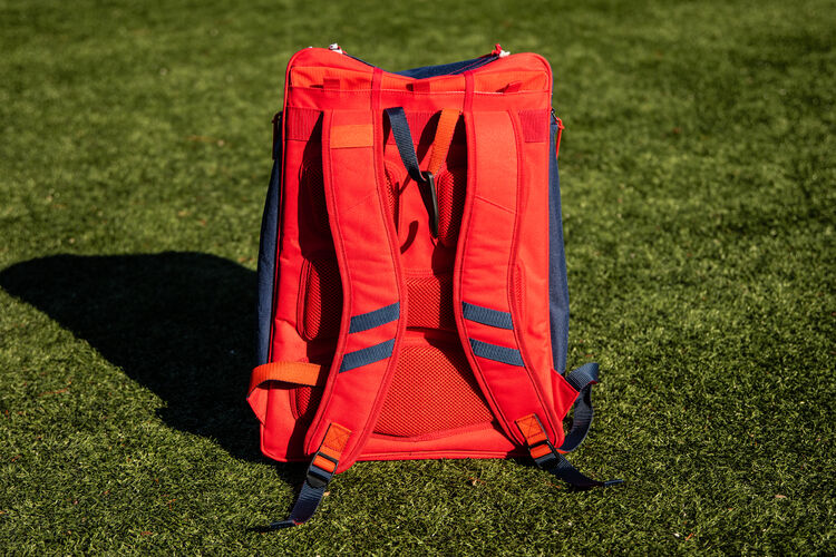 Red back of a USA Legion backpack sitting on a field with red shoulder straps - SKU: LEGION-USA