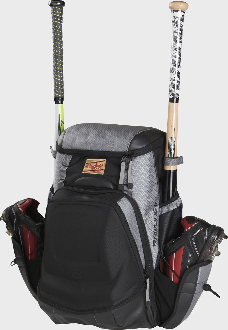 Front left of a black/gray R1000 Gold Glove equipment bag filled with cleats and bats in the side compartments