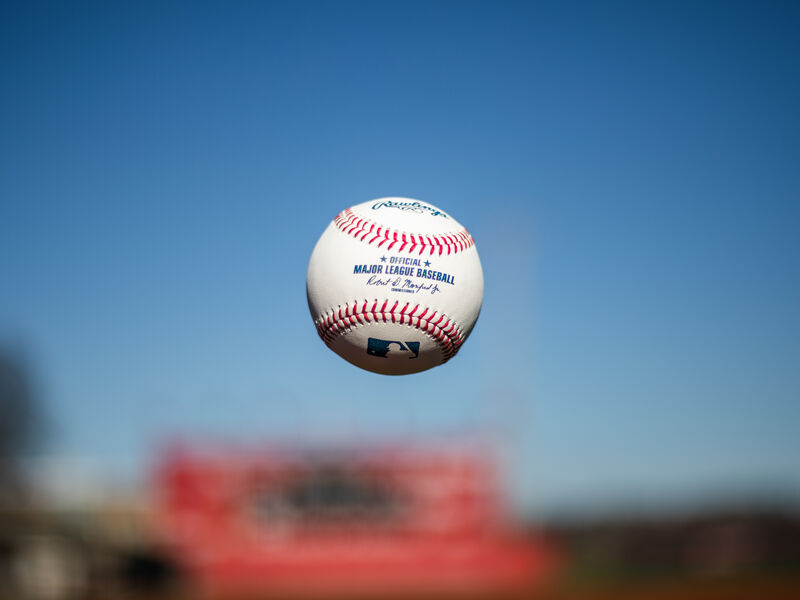 A Rawlings Official MLB baseball being tossed in the air with the sky in the background - SKU: ROMLB