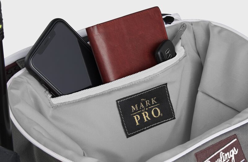 Zippered pocket in the top storage compartment of a maroon Impulse backpack with a phone, wallet and keys - SKU: IMPLSE-MA