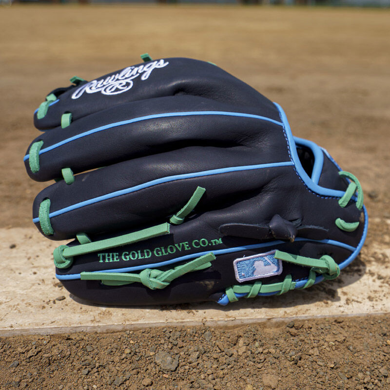 Picture of the back of a navy exclusive Rawlings NXT Series 11.5" infield glove on a pitching rubber