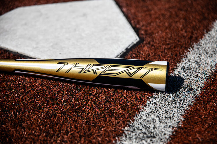 Gold barrel of a Rawlings Threat bat lying next to home plate - SKU: USZT12