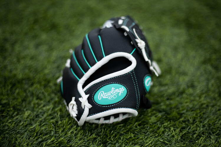 Mint Rawlings logo on a wrist strap of a youth Players glove lying on a field - SKU: PL10BMT