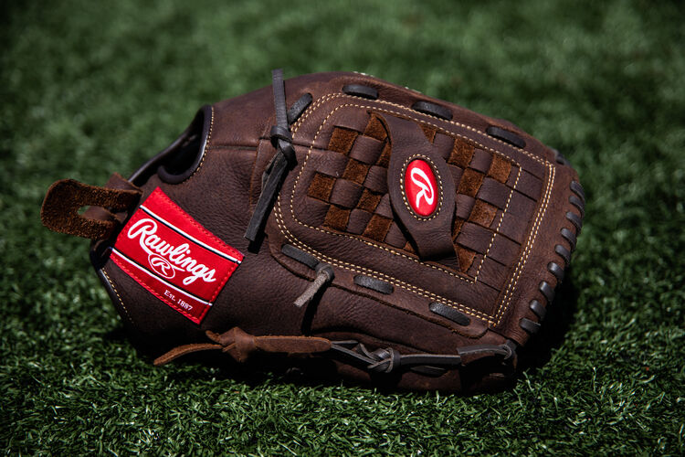 A brown Player Preferred Basket Web glove lying on a field - SKU: P140BPS