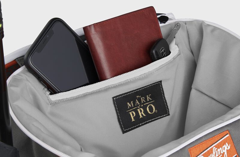 Zippered pocket in the top storage compartment of an orange Impulse backpack with a phone, wallet and keys - SKU: IMPLSE-BO