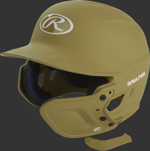 A Vegas gold MEXTR attached to a Mach batting helmet with the removable TPU piece off to show the hardware