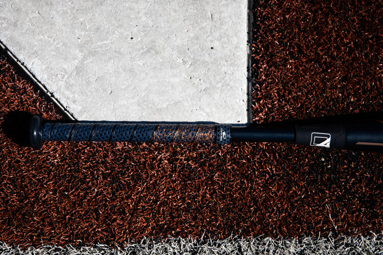 Handle of a Rawlings Quatro Pro fastpitch bat lying next to home plate - SKU: FPZP9