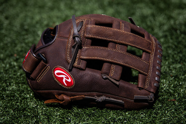 A brown Player Preferred H-web glove lying on a field - SKU: P130HFL
