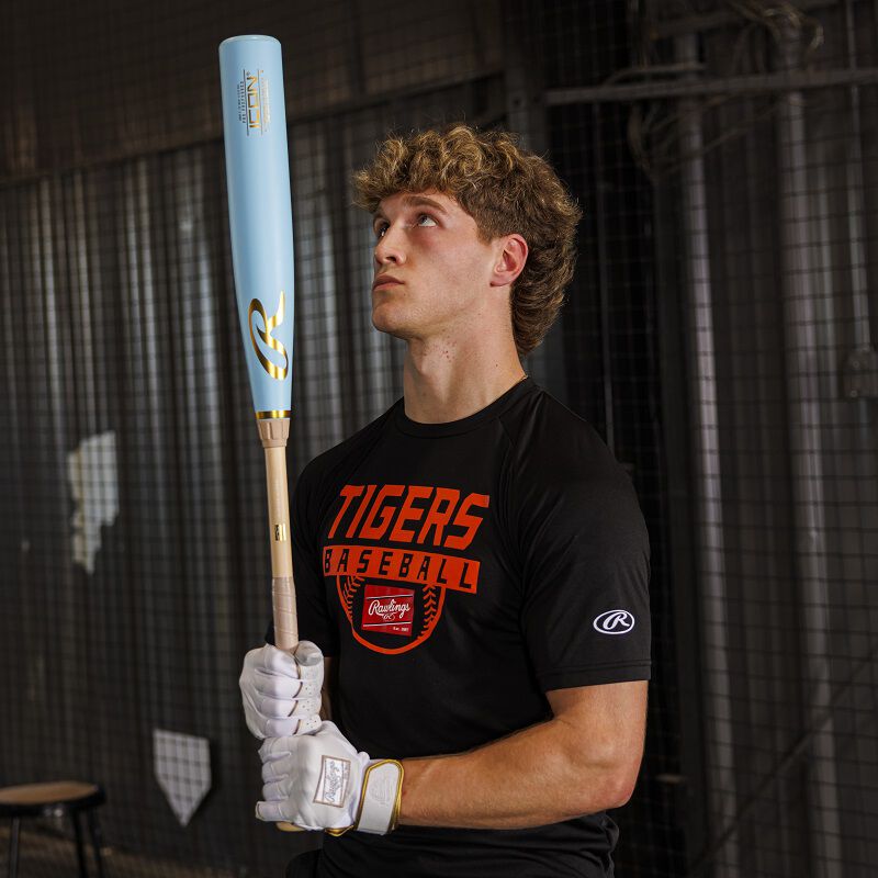 A player holding and looking at the barrel of a Rawlings Icon Pro Preferred BBCOR baseball bat