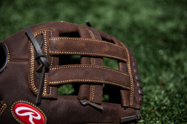 Brown H-web on a Rawlings Player Preferred 13-inch glove lying on a field - SKU: P130HFL