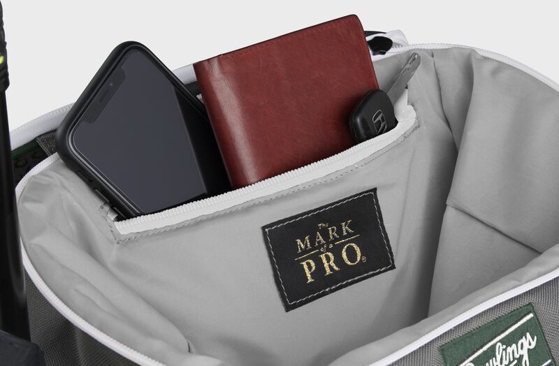 Zippered pocket in the top storage compartment of a dark green Impulse backpack with a phone, wallet and keys - SKU: IMPLSE-DG loading=