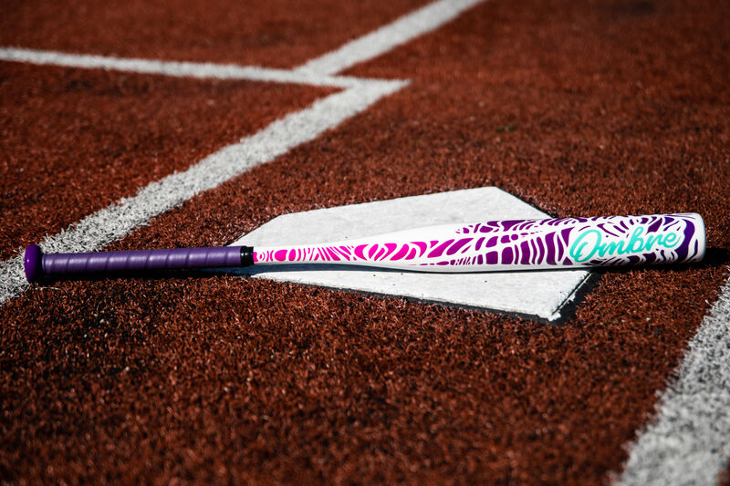 A Rawlings Ombre fastpitch bat lying on home plate of a field - SKU: FPZO11